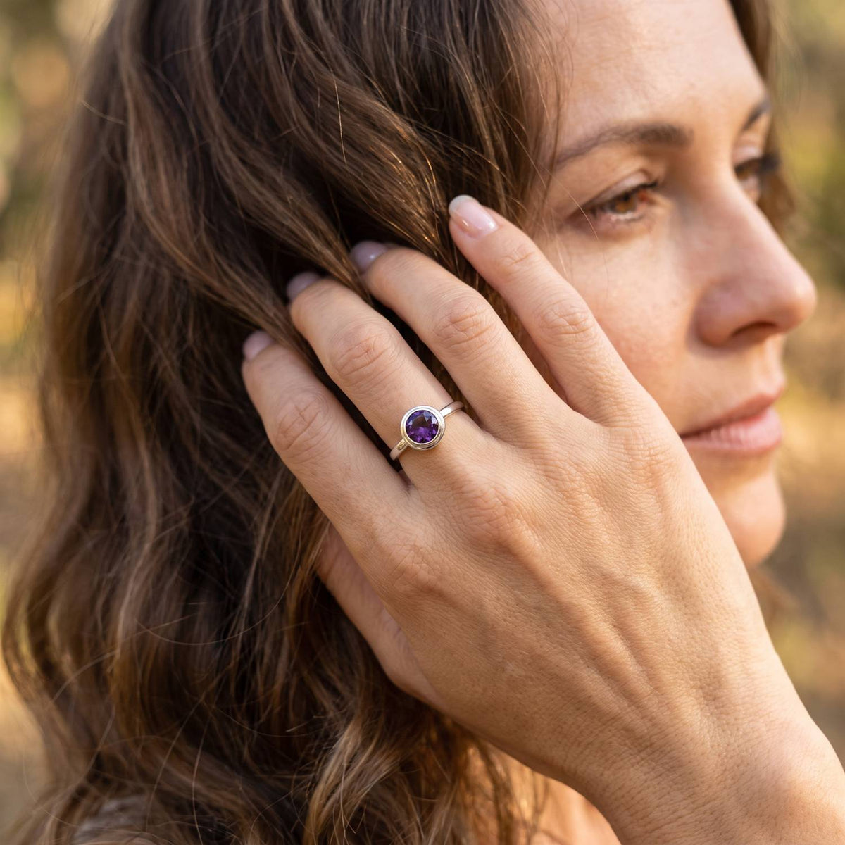 Frau trägt Silberring mit Amethyst an der Hand am Haar