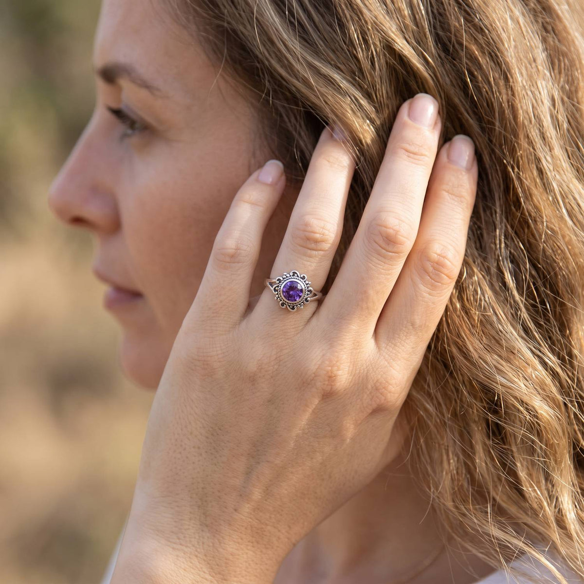Frau trägt Silberring mit Amethyst an der Hand am Haar