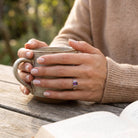 [KI] Amethystring aus Silber getragen beim Lesen mit einer Tasse