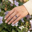 [KI] Silberring mit Amethyst an der Hand zwischen Blumen