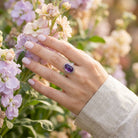 [KI] Silberring mit Amethyst an der Hand zwischen Blumen