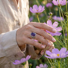 [KI] Silberring mit Amethyst an der Hand zwischen Blumen