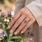 [KI] Silberring mit Amethyst an der Hand zwischen Blumen