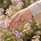 [KI] Silberring mit Amethyst an der Hand zwischen Blumen