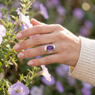 [KI] Silberring mit Amethyst an der Hand zwischen Blumen