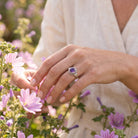 [KI] Silberring mit Amethyst an der Hand zwischen Blumen
