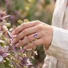 [KI] Silberring mit Amethyst an der Hand zwischen Blumen