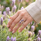 [KI] Silberring mit Amethyst an der Hand zwischen Blumen