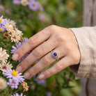 [KI] Silberring mit Amethyst an der Hand zwischen Blumen