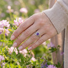 [KI] Silberring mit Amethyst an der Hand zwischen Blumen