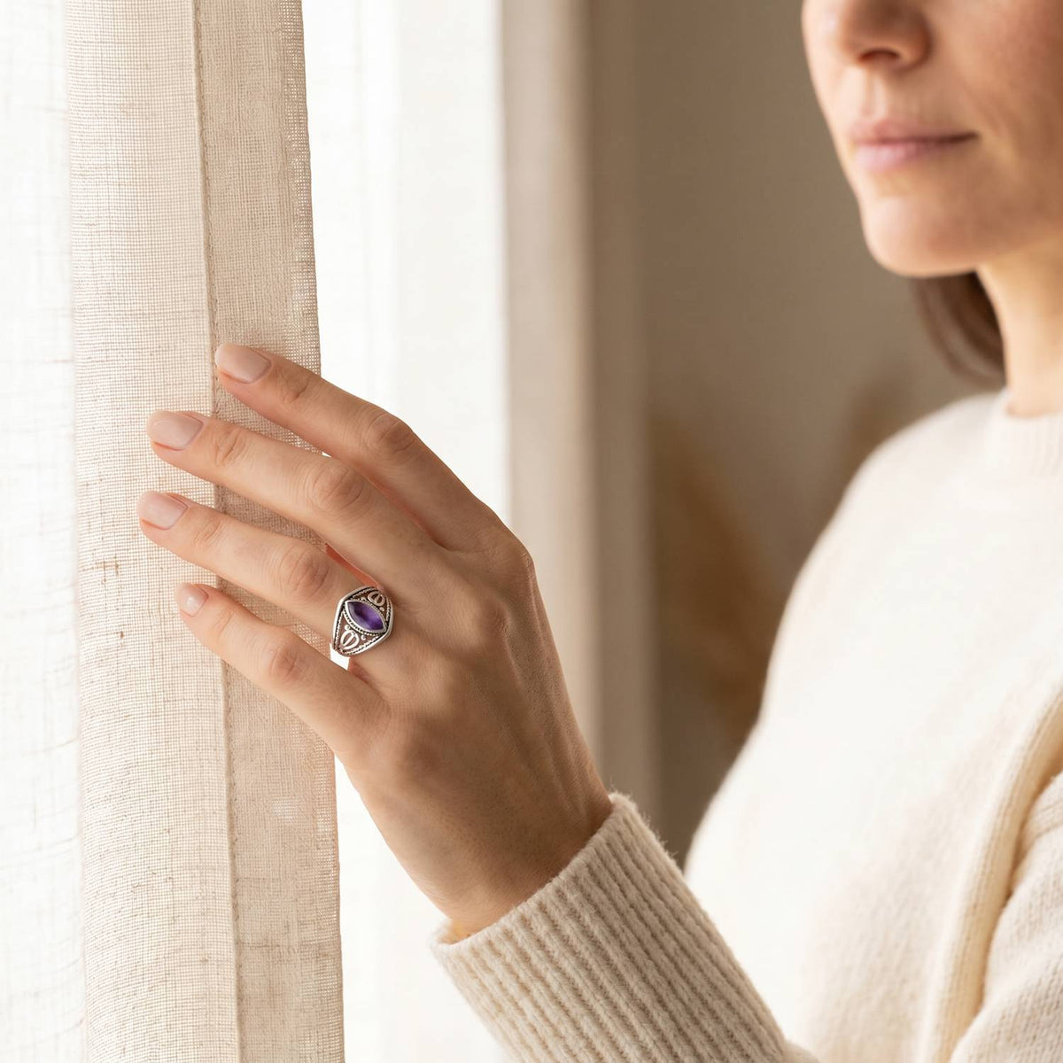 Frau trägt einen Amethystring aus Silber am Fenster