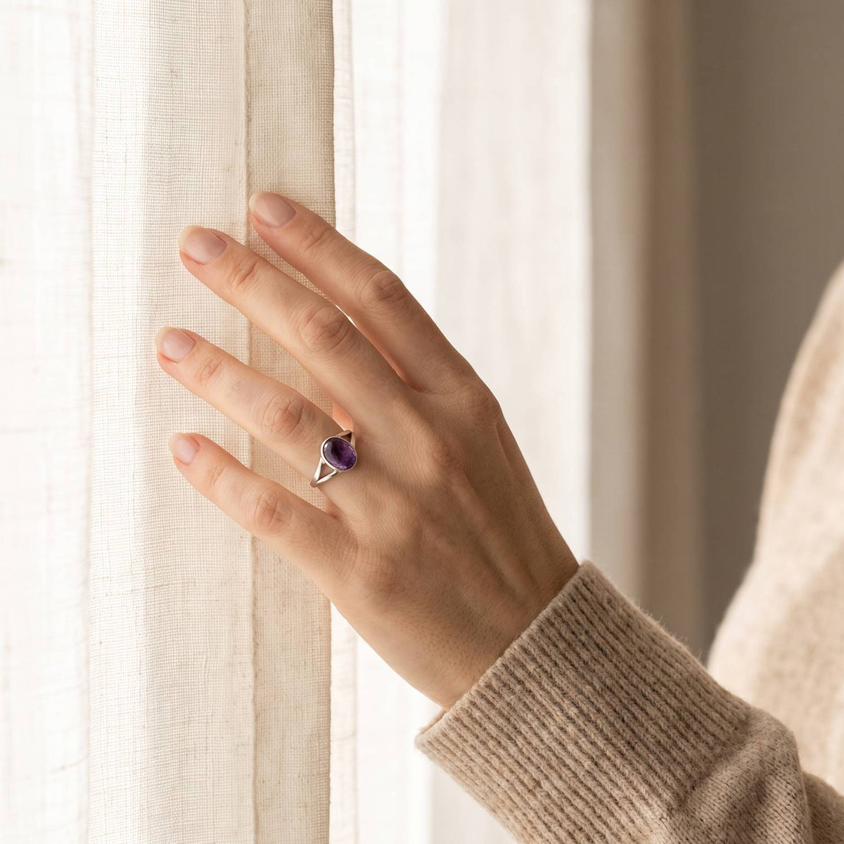 Frau trägt einen Amethystring aus Silber am Fenster