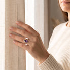 [KI] Frau trägt einen Amethystring aus Silber am Fenster