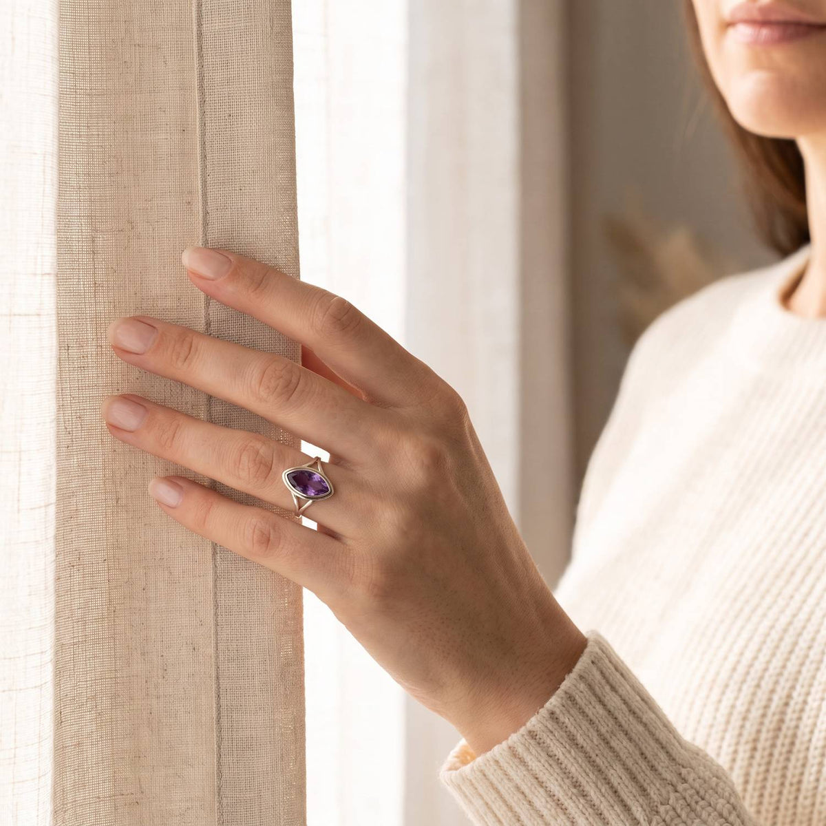 Frau trägt einen Amethystring aus Silber am Fenster