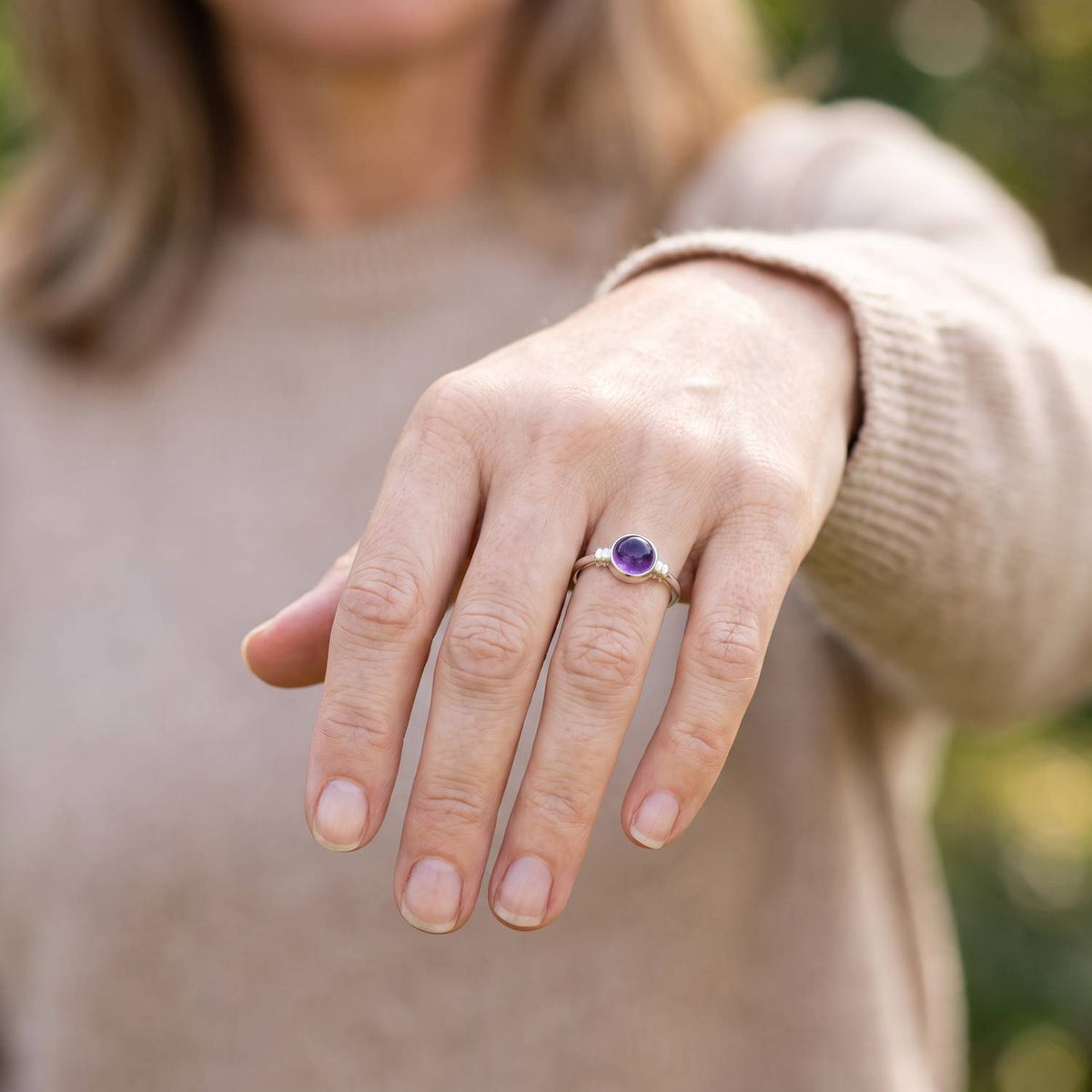 Amethystring aus Silber getragen an der Hand im Freien