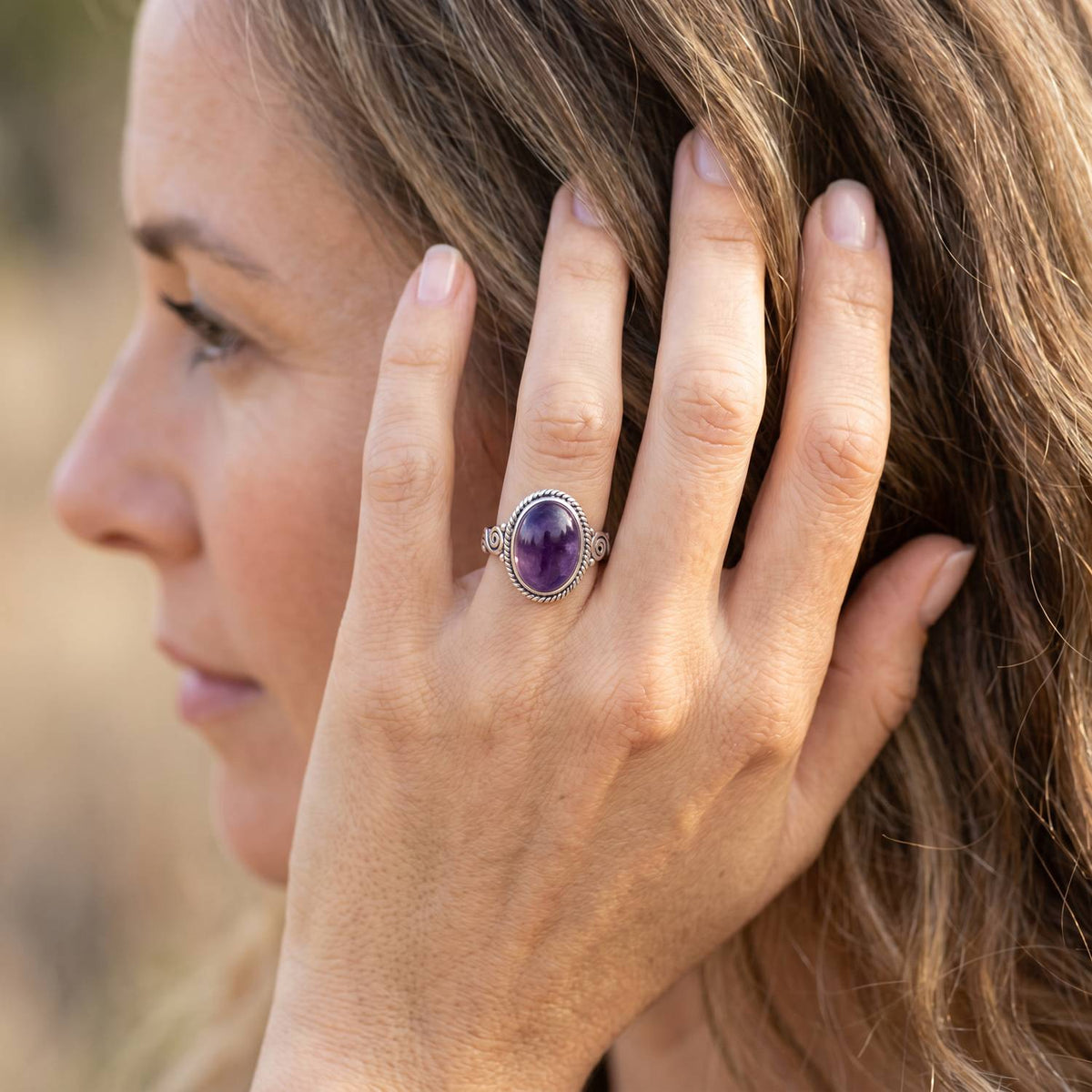 Frau trägt Silberring mit Amethyst an der Hand am Haar