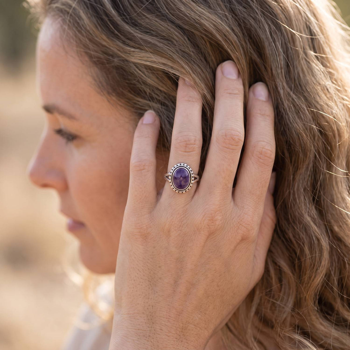 Frau trägt Silberring mit Amethyst an der Hand am Haar