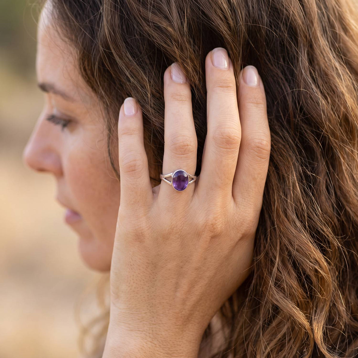 Frau trägt Silberring mit Amethyst an der Hand am Haar