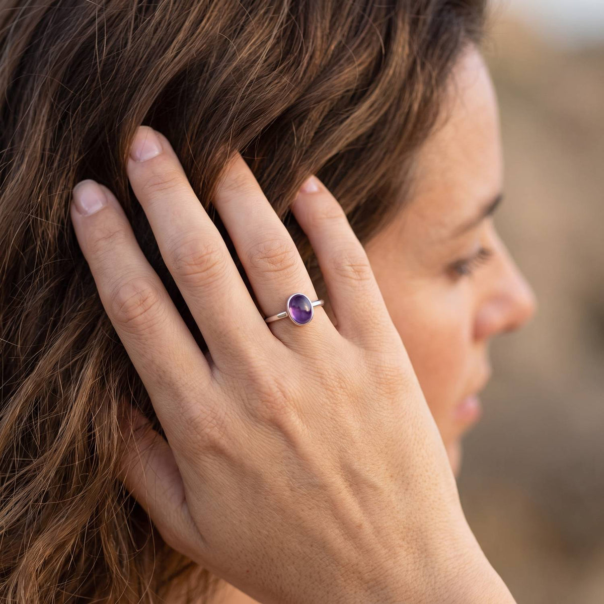 Frau trägt Silberring mit Amethyst an der Hand am Haar