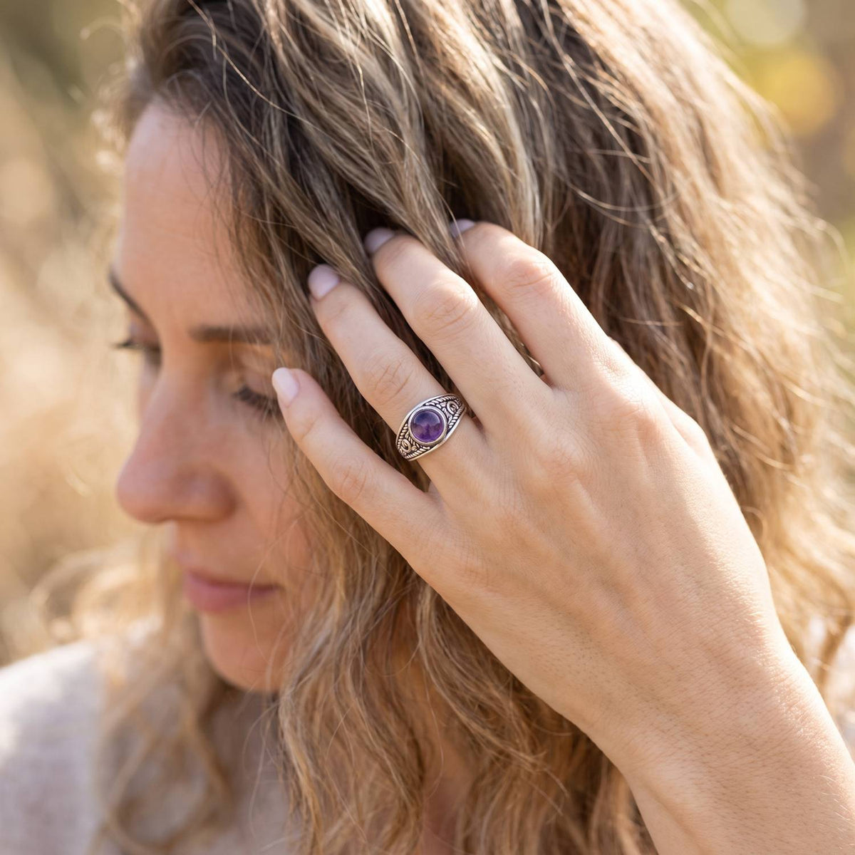 Frau trägt Silberring mit Amethyst an der Hand am Haar