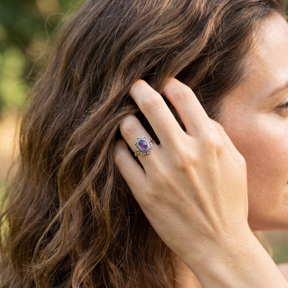 Frau trägt Silberring mit Amethyst an der Hand am Haar