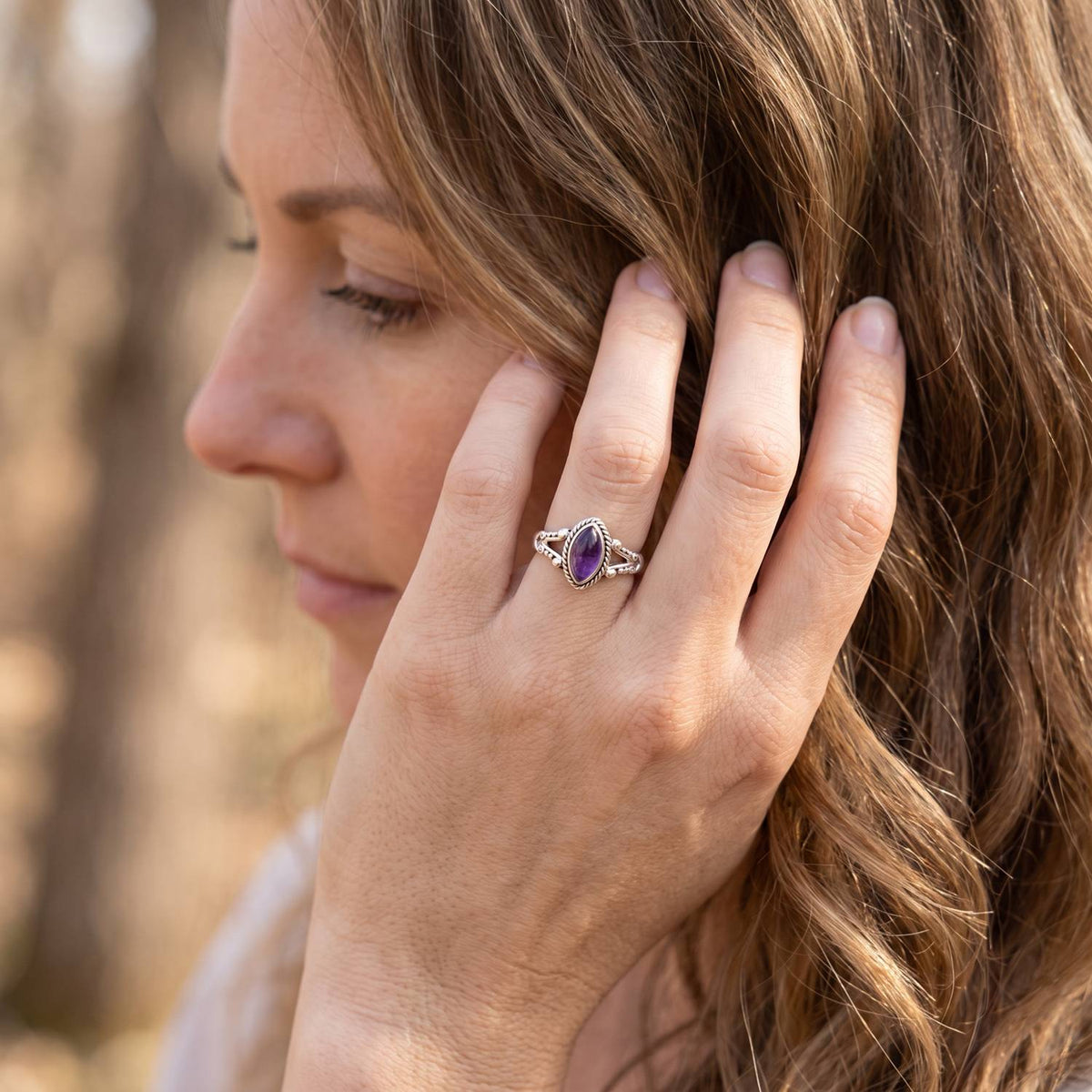 Frau trägt Silberring mit Amethyst an der Hand am Haar