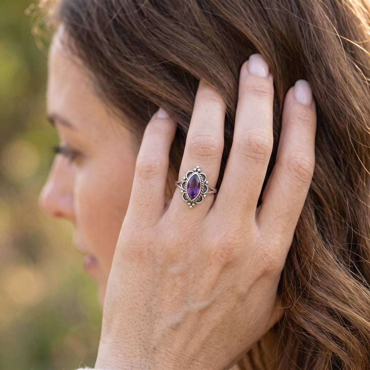 Frau trägt Silberring mit Amethyst an der Hand am Haar