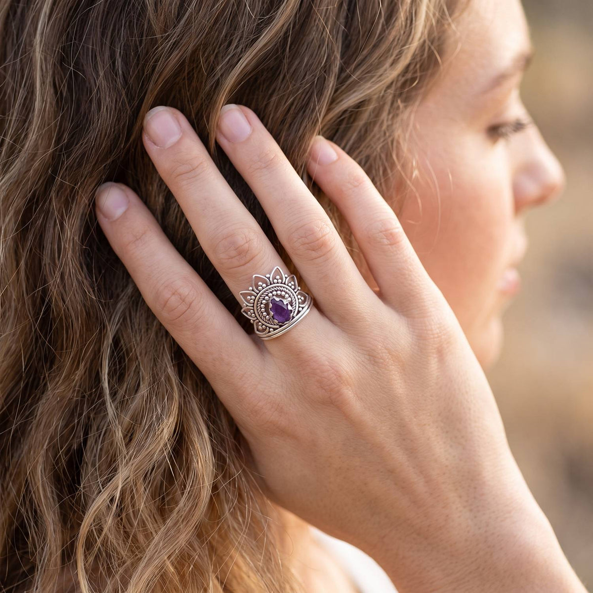 Frau trägt Silberring mit Amethyst an der Hand am Haar