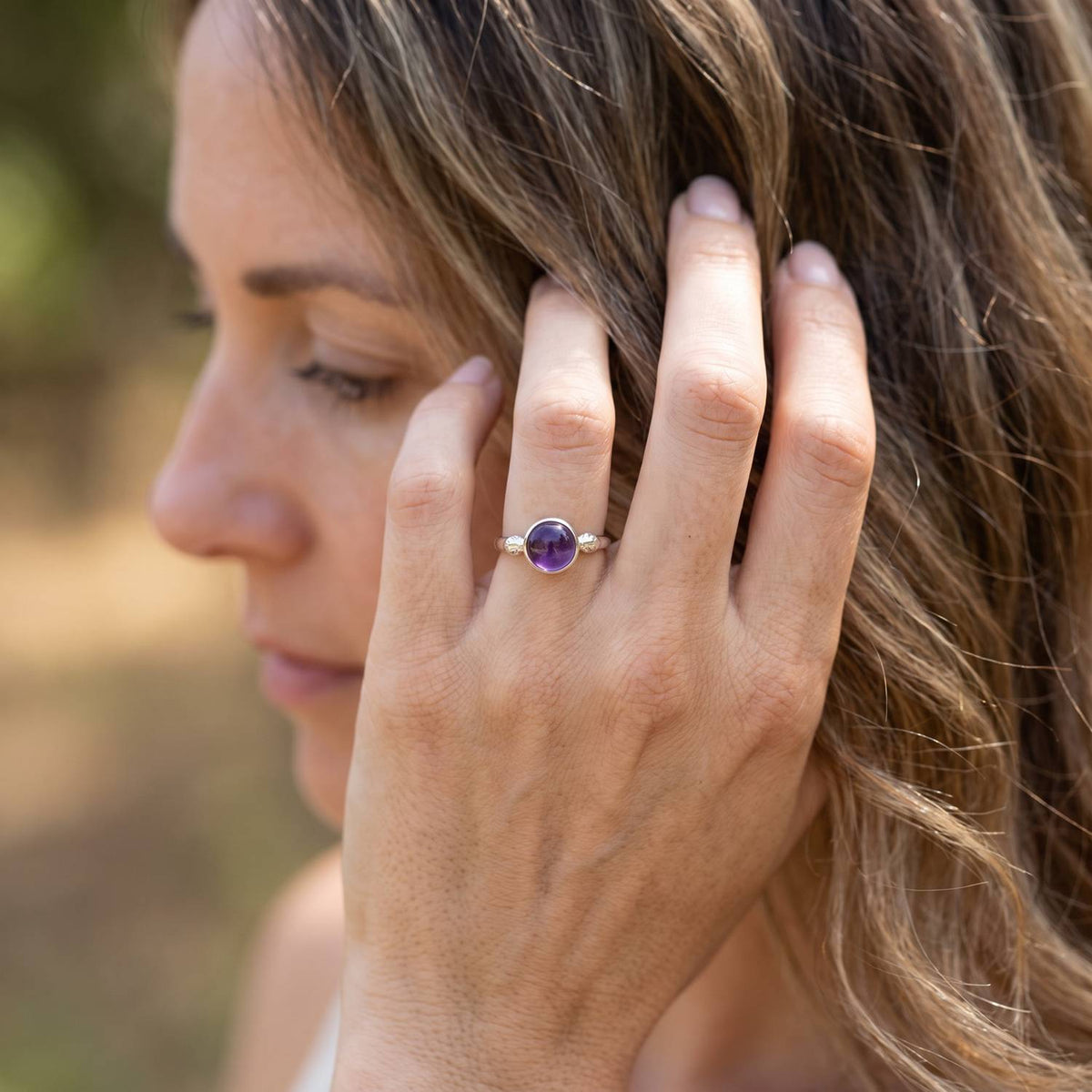 Frau trägt Silberring mit Amethyst an der Hand am Haar