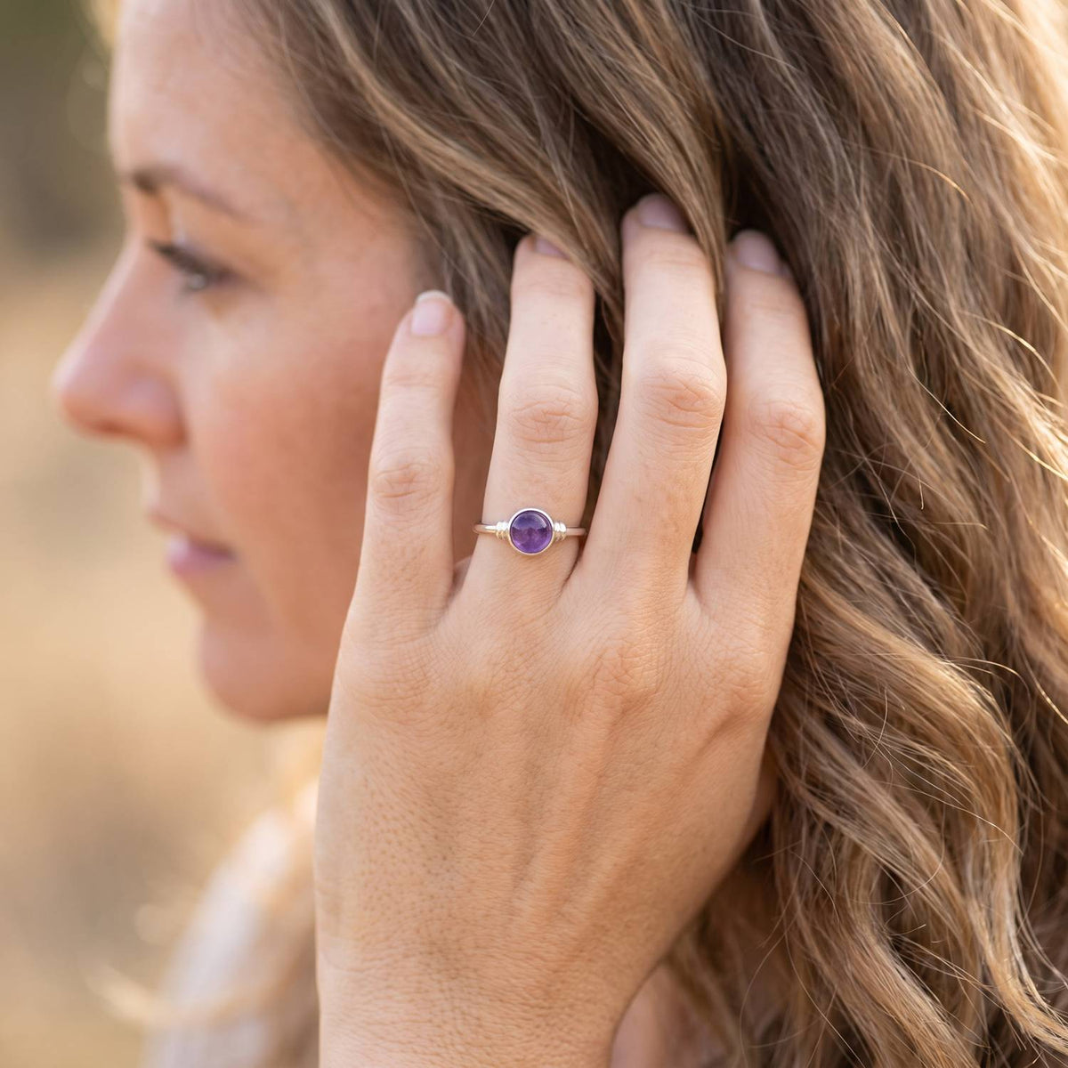 Frau trägt Silberring mit Amethyst an der Hand am Haar