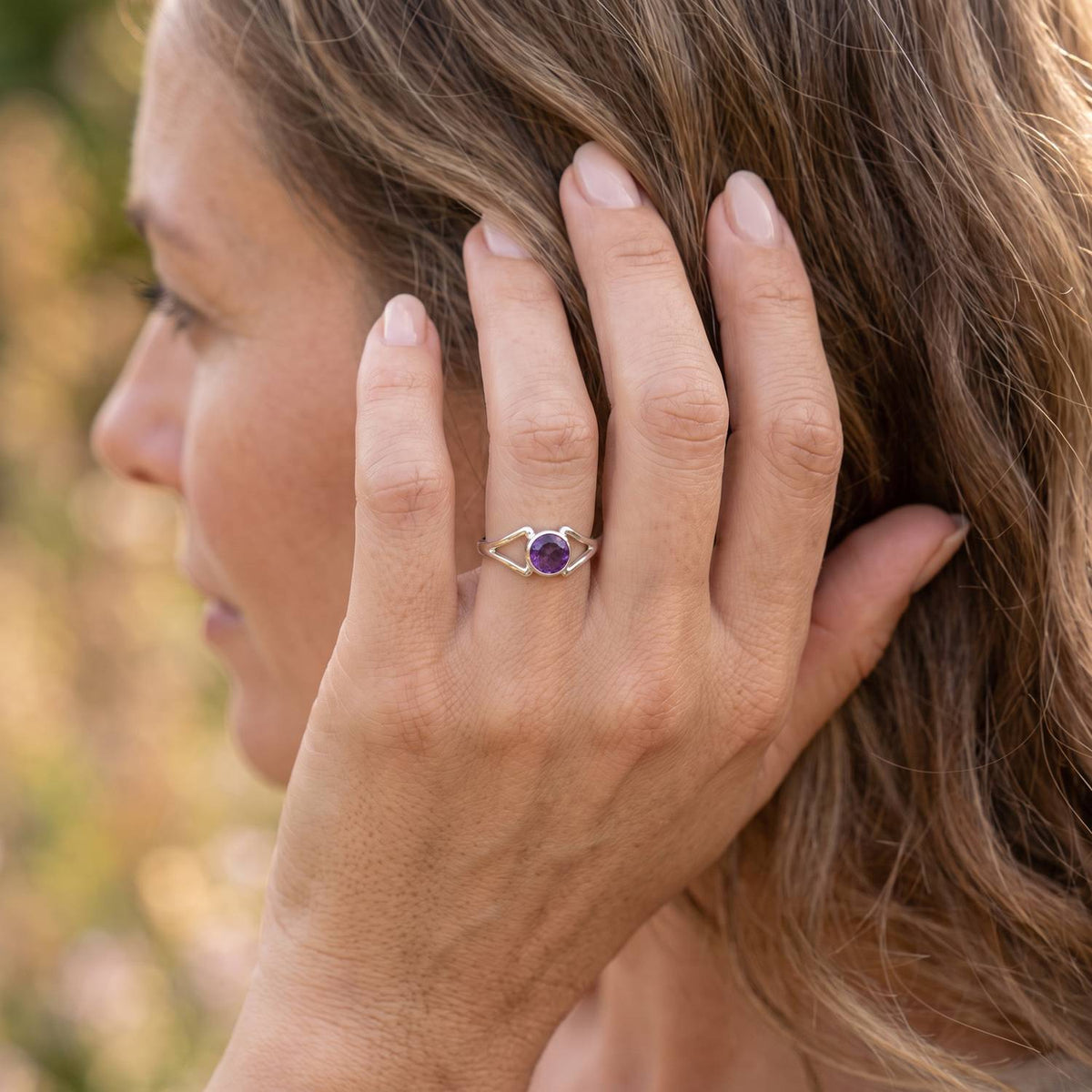 Frau trägt Silberring mit Amethyst an der Hand am Haar