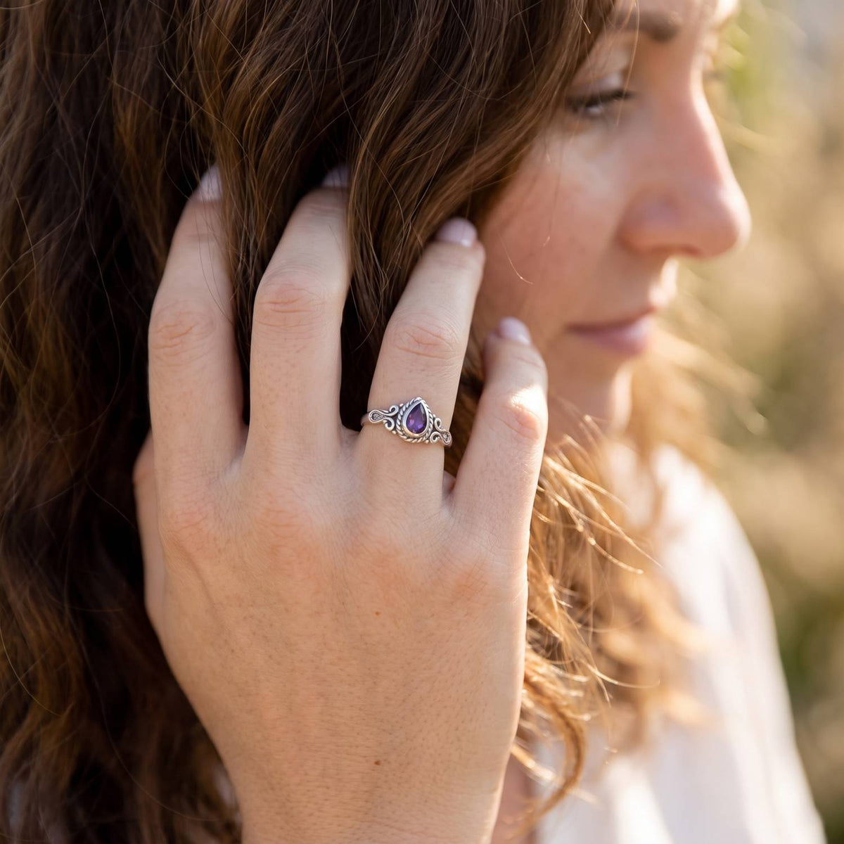 Frau trägt Silberring mit Amethyst an der Hand am Haar