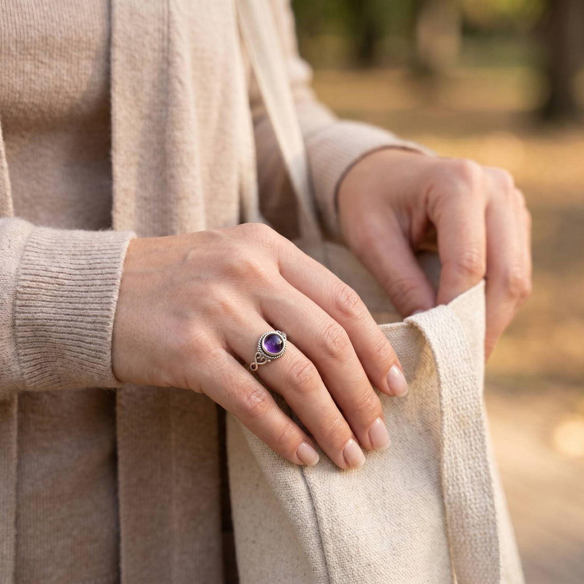 Frau trägt Silberring mit Amethyst beim Griff in eine Tasche