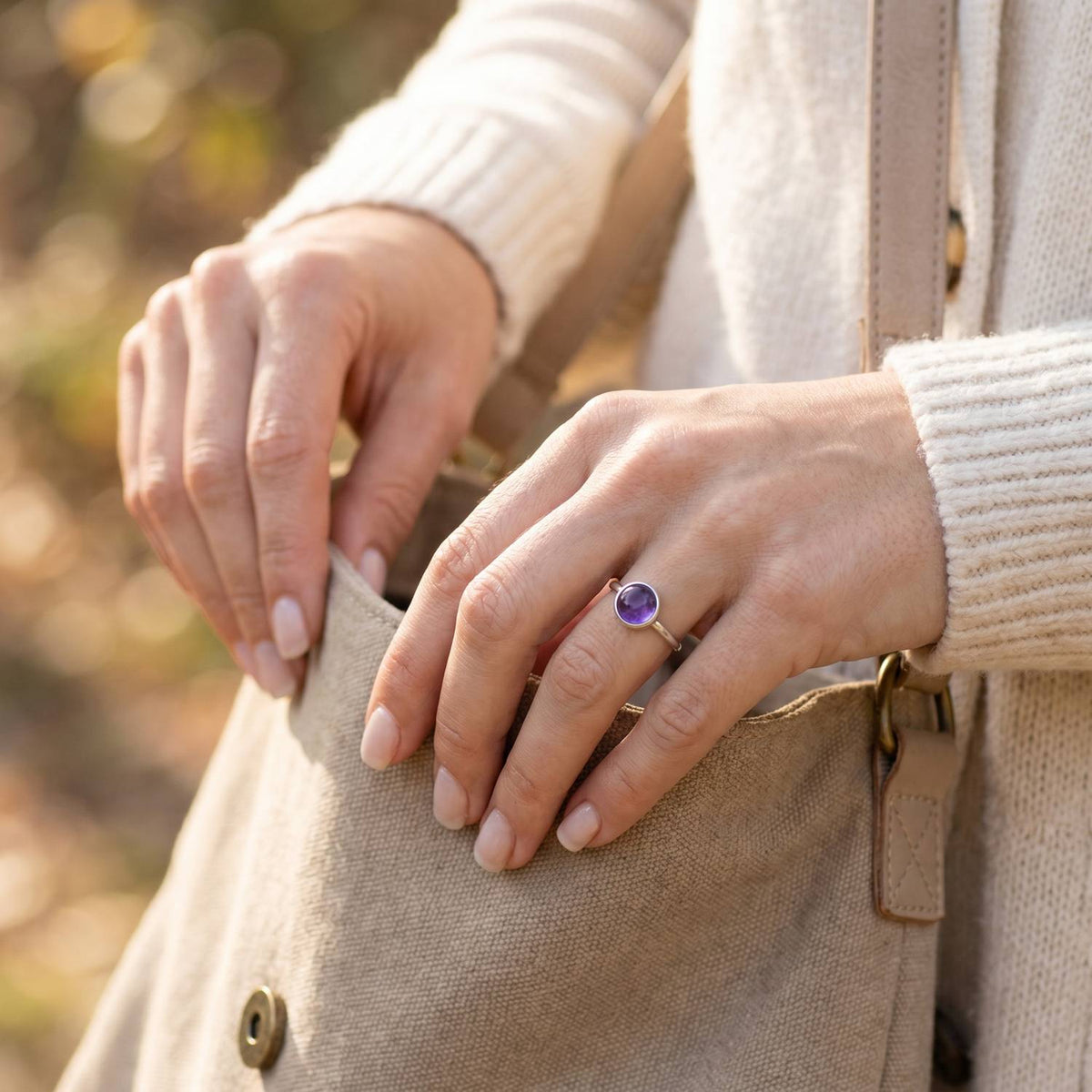 Frau trägt Silberring mit Amethyst beim Griff in eine Tasche