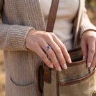 [KI] Frau trägt Silberring mit Amethyst beim Griff in eine Tasche