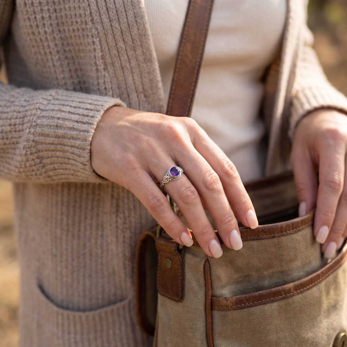 Frau trägt Silberring mit Amethyst beim Griff in eine Tasche