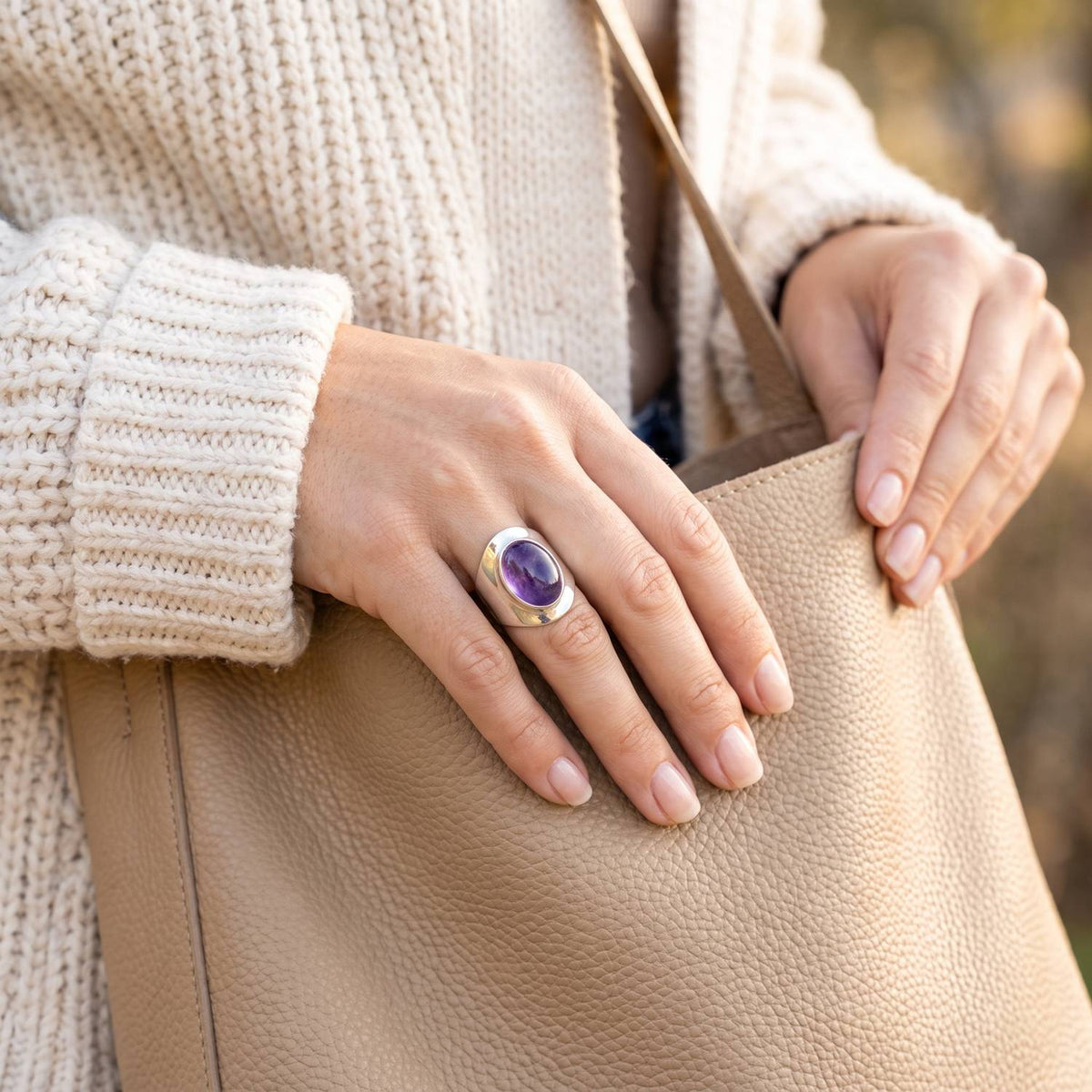 Frau trägt Silberring mit Amethyst beim Griff in eine Tasche