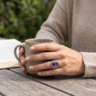 [KI] Amethystring aus Silber getragen beim Lesen mit einer Tasse