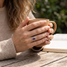 [KI] Amethystring aus Silber getragen beim Lesen mit einer Tasse