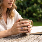 [KI] Amethystring aus Silber getragen beim Lesen mit einer Tasse