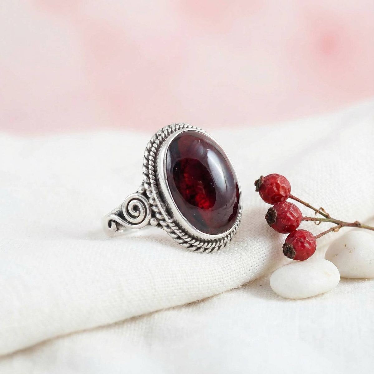 Silberring mit Granat auf hellem Stoff
