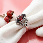 [KI] Silberring mit Granat auf hellem Stoff