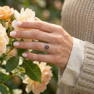 [KI] Silberring mit Granat an der Hand zwischen Blumen