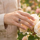 [KI] Silberring mit Granat an der Hand zwischen Blumen
