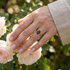 [KI] Silberring mit Granat an der Hand zwischen Blumen