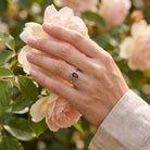 [KI] Silberring mit Granat an der Hand zwischen Blumen