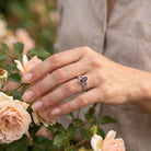 [KI] Silberring mit Granat an der Hand zwischen Blumen