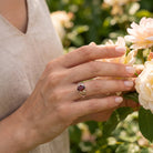 [KI] Silberring mit Granat an der Hand zwischen Blumen