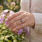 [KI] Silberring mit Granat an der Hand zwischen Blumen