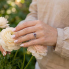 [KI] Silberring mit Granat an der Hand zwischen Blumen